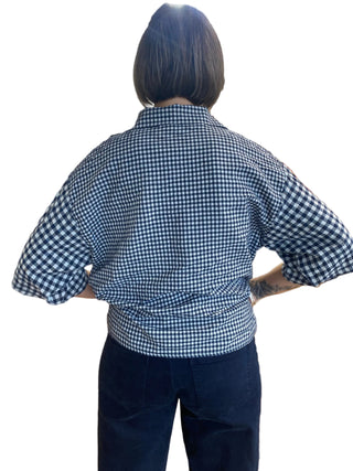 Person wearing a blue and white checkered shirt with navy pants on a white background